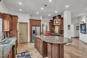 Kitchen with arched walkways, decorative backsplash, an island with sink, stainless steel refrigerator with ice dispenser, and a sink