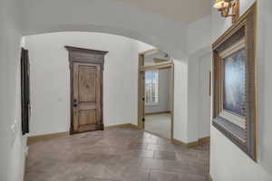 Entryway featuring arched walkways, tile patterned floors, and baseboards