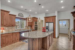 Kitchen with appliances with stainless steel finishes, brown cabinets, a sink, and tasteful backsplash