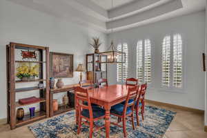 Dining space featuring a notable chandelier, a tray ceiling, baseboards, and a healthy amount of sunlight