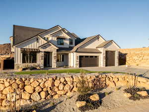 View of front of home featuring stone siding, board and batten siding, an attached garage, and fence