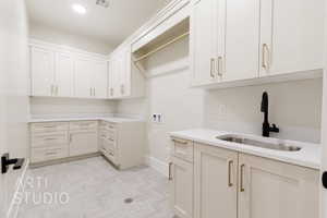 Clothes washing area featuring washer hookup, a sink, visible vents, baseboards, and cabinet space