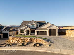 View of front of property featuring decorative driveway, a tile roof, an attached garage, board and batten siding, and stone siding