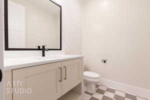 Half bath with toilet, vanity, baseboards, and tile patterned floors