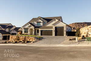 View of front of property featuring an attached garage, stone siding, decorative driveway, and board and batten siding