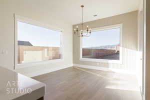 Unfurnished dining area featuring a chandelier, visible vents, plenty of natural light, and wood finished floors