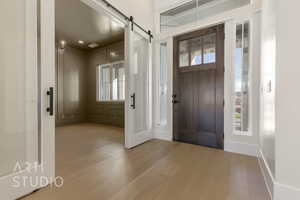 Foyer entrance featuring wood finished floors, visible vents, baseboards, and a barn door