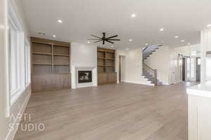 Unfurnished living room with stairs, a glass covered fireplace, recessed lighting, and a barn door