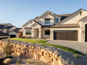 Modern farmhouse style home featuring a garage, stone siding, decorative driveway, board and batten siding, and a front yard