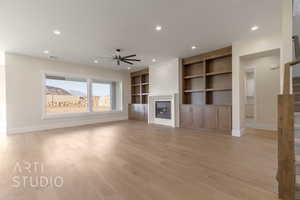 Unfurnished living room with light wood-style floors, a glass covered fireplace, stairway, and recessed lighting