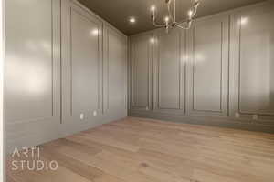 Empty room with a chandelier, a decorative wall, wood finished floors, and recessed lighting