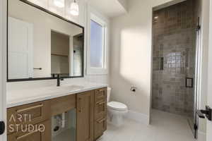 Full bathroom with baseboards, toilet, tile patterned flooring, a tile shower, and vanity