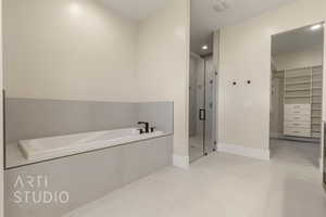 Bathroom with a garden tub, a shower stall, a spacious closet, and baseboards