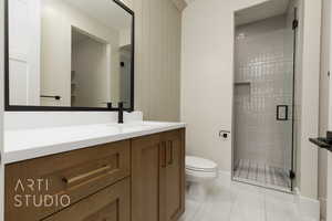 Bathroom featuring toilet, a stall shower, and vanity