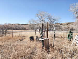 View of yard with fence and a rural view