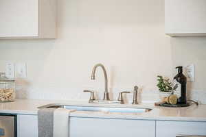 Interior details with light stone countertops, white cabinets, and a sink