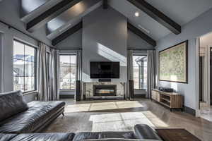 Living area with plenty of natural light, a fireplace, high vaulted ceiling, and beamed ceiling