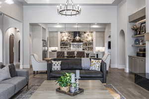 Living room with arched walkways, an inviting chandelier, baseboards, and wood finished floors