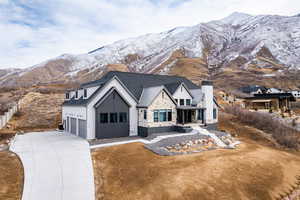 Modern farmhouse featuring a chimney, concrete driveway, a standing seam roof, a mountain view, and metal roof