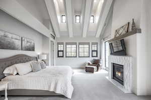 Carpeted bedroom featuring high vaulted ceiling, a high end fireplace, and beamed ceiling