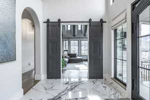 Foyer with marble finish floor, a barn door, and a wealth of natural light