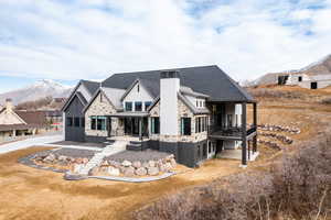 View of front of home featuring metal roof, a mountain view, stone siding, a standing seam roof, and a chimney