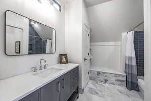 Full bath featuring marble finish floor, a shower with shower curtain, and vanity