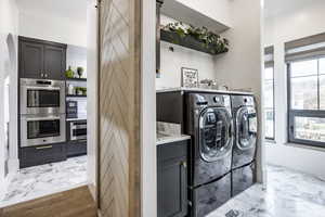 Washroom featuring marble finish floor, a barn door, cabinet space, and washer and dryer