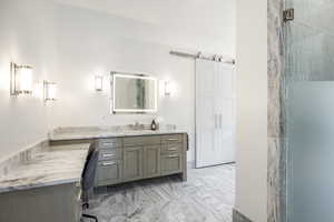 Full bath featuring marble finish floor, a shower with door, and vanity