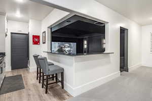 Kitchen featuring light wood-style floors, a kitchen bar, and baseboards