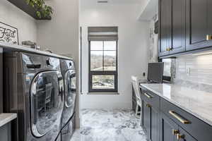 Laundry room featuring washing machine and dryer, marble finish floor, cabinet space, and baseboards