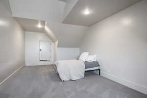 Bedroom featuring vaulted ceiling, carpet, and baseboards