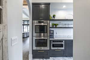 Kitchen featuring arched walkways, backsplash, and stainless steel double oven