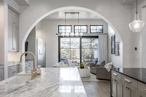 Kitchen featuring light stone countertops, gray cabinets, open floor plan, a sink, and wood finished floors