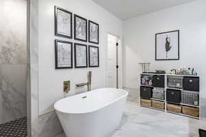 Full bathroom featuring marble finish floor and a soaking tub