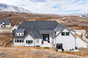 Rear view of property featuring a shingled roof, a mountain view, and stucco siding