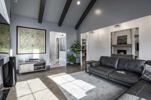 Living area with baseboards, arched walkways, beamed ceiling, high vaulted ceiling, and a high end fireplace