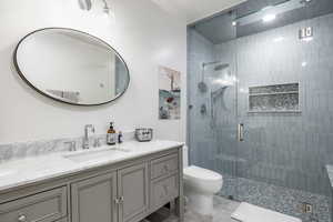 Bathroom featuring toilet, tiled shower, and vanity