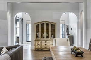 Dining room with arched walkways, wood finished floors, and a barn door