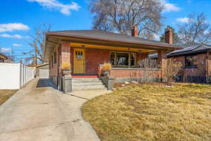 View of front of property featuring an outbuilding, brick siding, a porch, a front yard, and fence