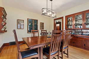 Dining area with light wood-style floors, visible vents, a notable chandelier, and baseboards