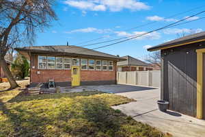 Rear view of house featuring a yard, brick siding, a patio area, and fence