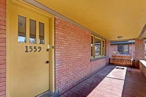 Entrance to property with a porch and brick siding