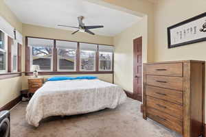 Carpeted bedroom with a ceiling fan and baseboards