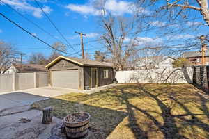 View of yard featuring a garage, an outbuilding, a fenced backyard, and a patio