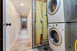 Laundry room featuring baseboards, laundry area, recessed lighting, and stacked washer / drying machine