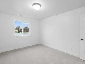 Empty room with a textured ceiling, baseboards, light carpet, and visible vents