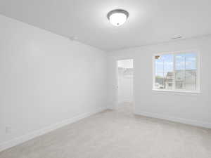 Empty room featuring visible vents, baseboards, a textured ceiling, and light colored carpet