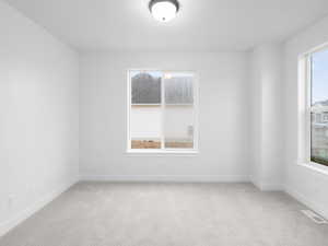 Spare room featuring light colored carpet, baseboards, and visible vents