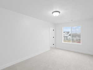 Spare room featuring baseboards, a textured ceiling, and light carpet